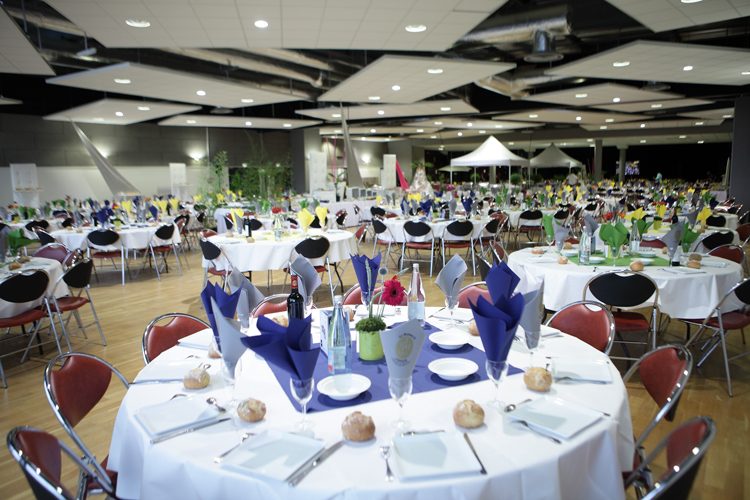 Salle Espace Glenmor dressée pour un dîner avec tables rondes, nappes blanches et centres de table