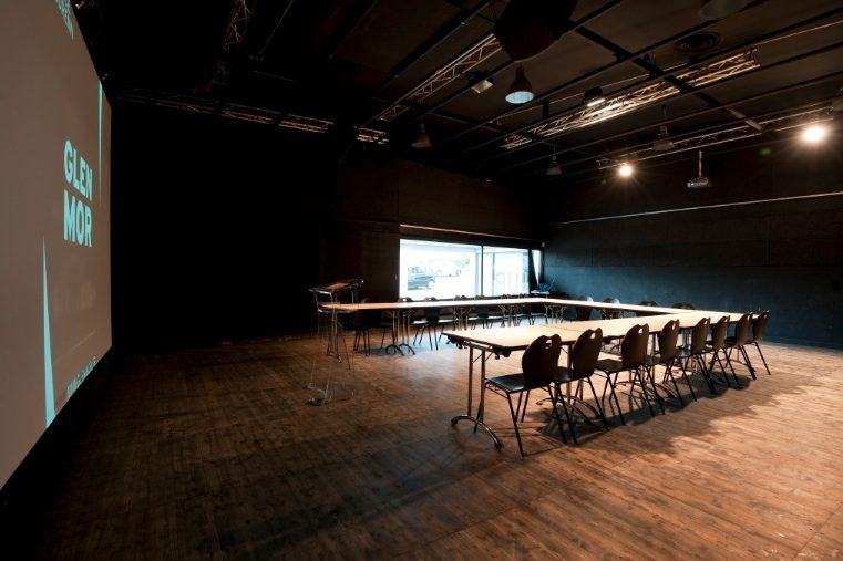 Salle de réunion Espace Glenmor configurée en U avec écran de projection et pupitre transparent