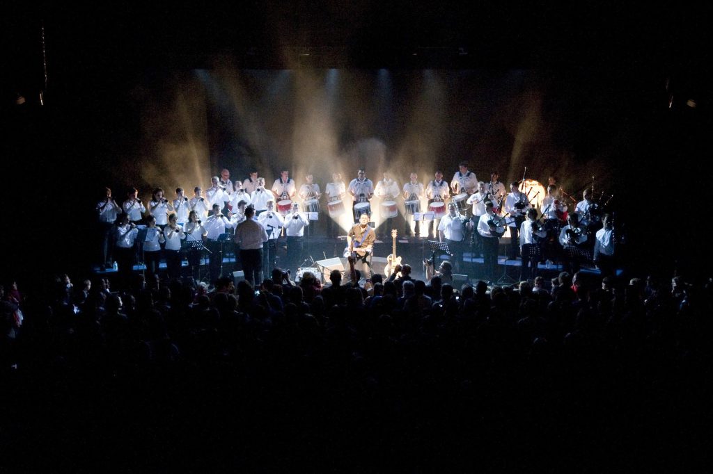 Concert sur la scène de l'Espace Glenmor avec artiste sous projecteurs et ensemble musical